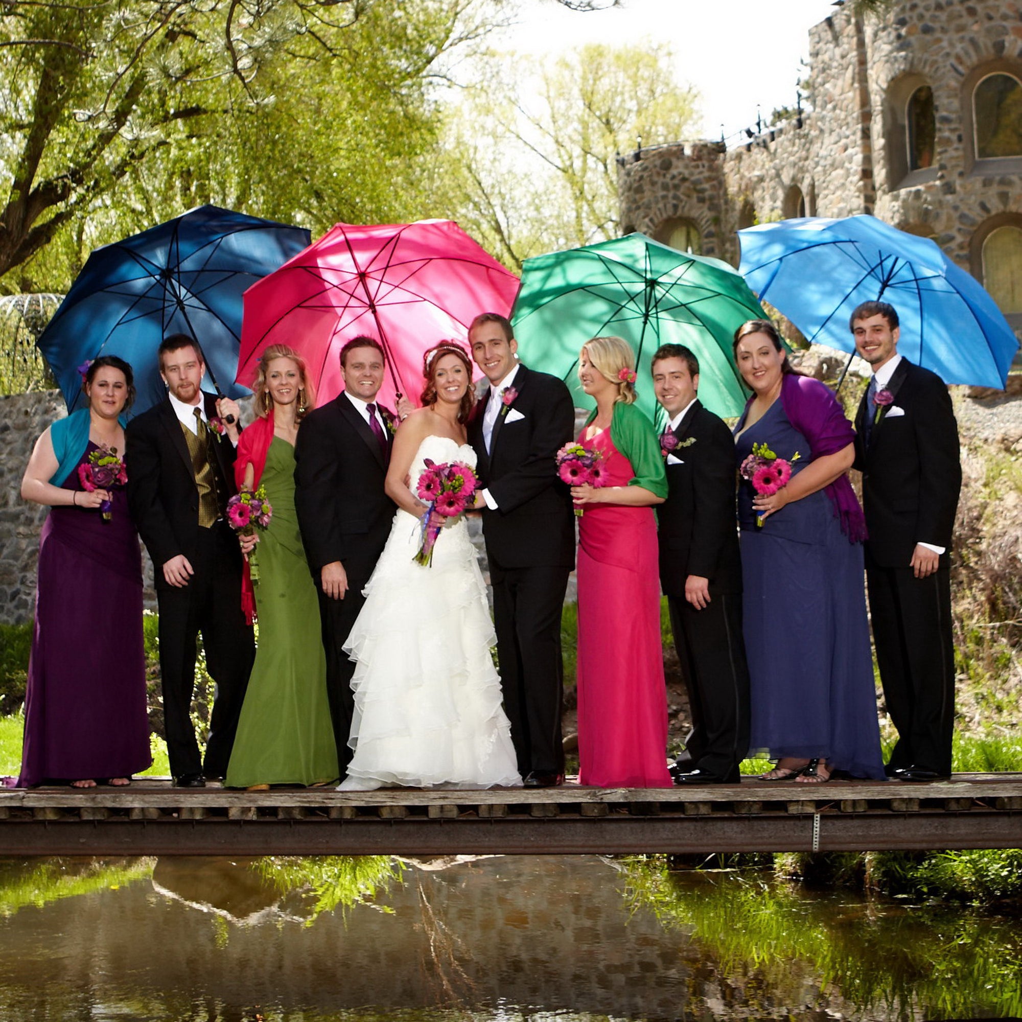 Bride and groom surrounded by couples each with an umbrella.