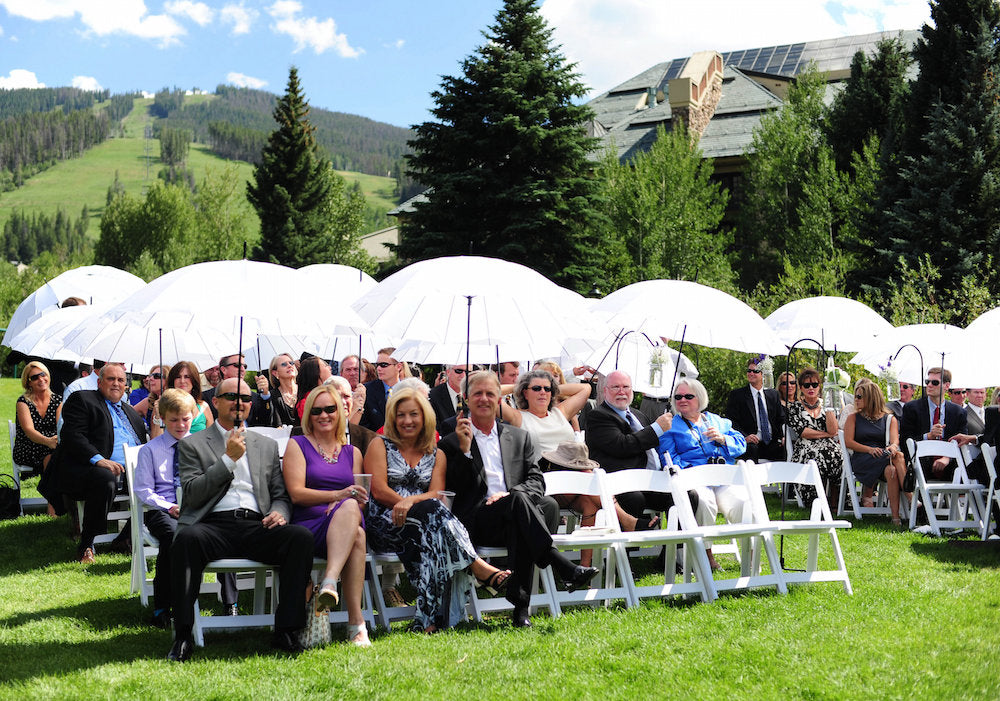 Guests shaded from sun by umbrellas at wedding Beaver Creek Colorado