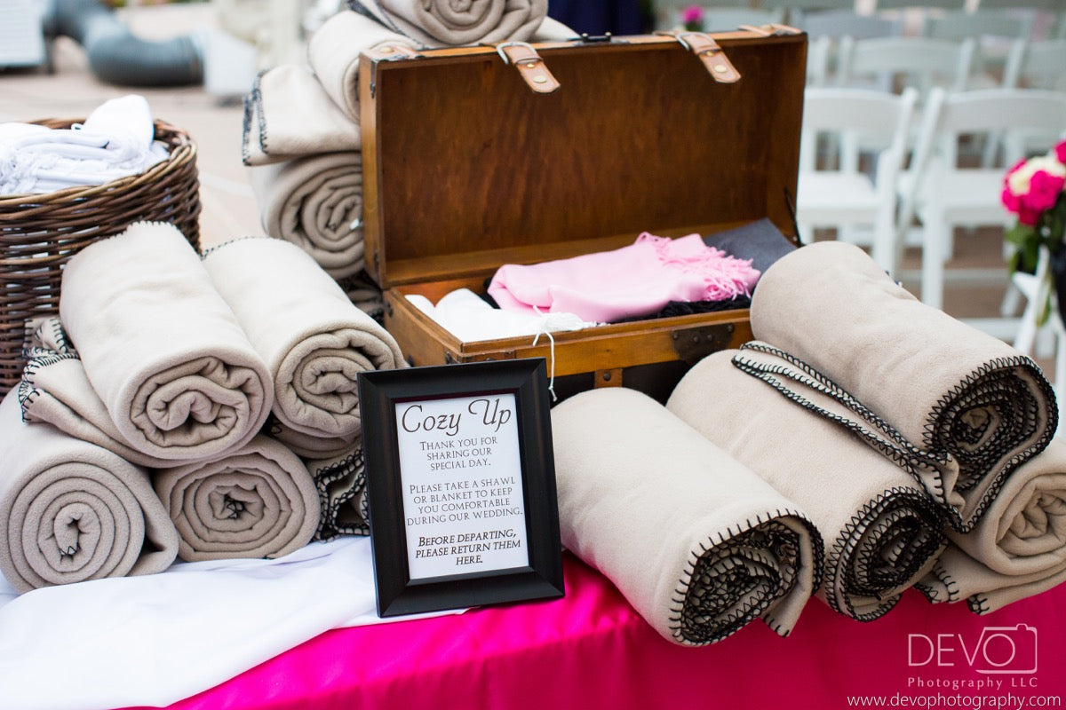 Tan fleece blankets paired with shawls for guests at an unseasonably chilly summer wedding. Credit: Devo Photography